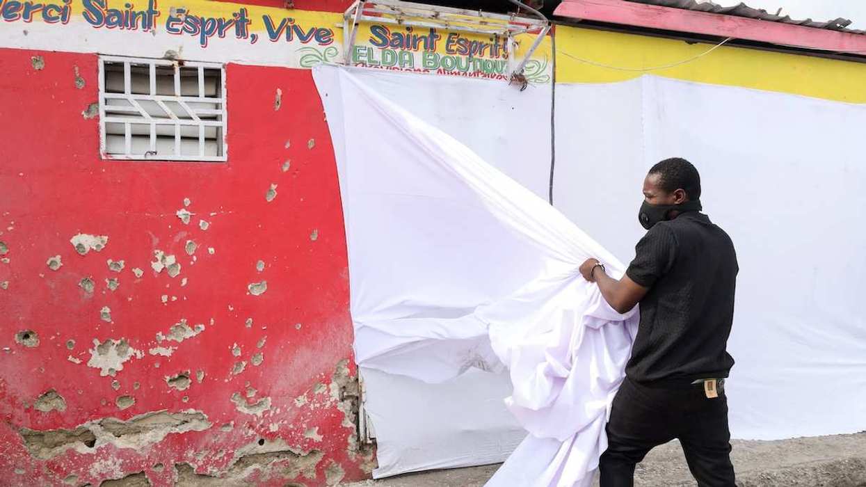 A man removes a sheet from a wall with shrapnel holes at the site of a drone attack on a birthday party, in Port-au-Prince, Haiti, on October 4, 2025.