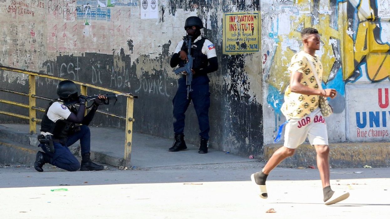 A man rushes past members of security forces during clashes between gangs and security forces, in Port-au-Prince, Haiti November 11, 2024.