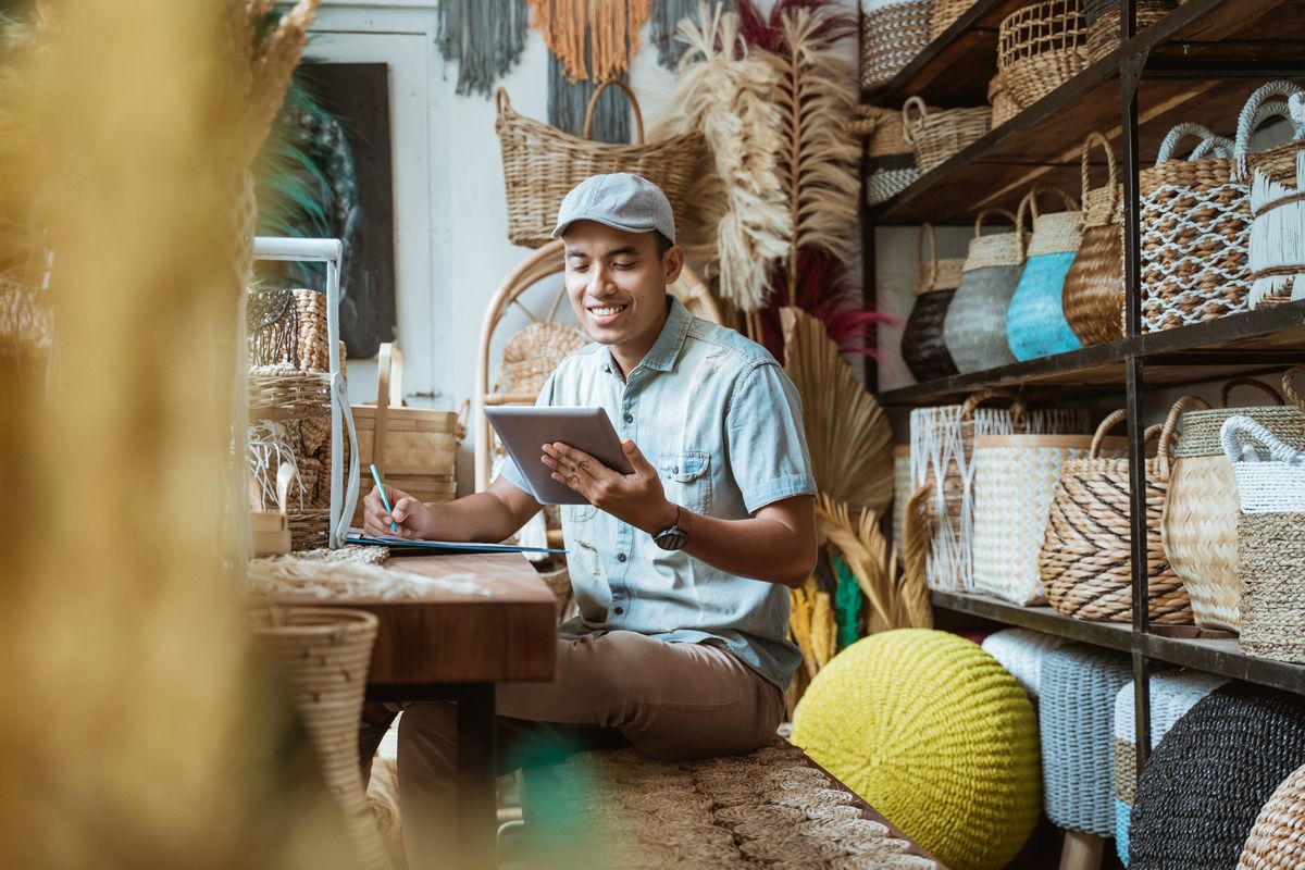 A man taking notes from a tablet in a store selling woven baskets