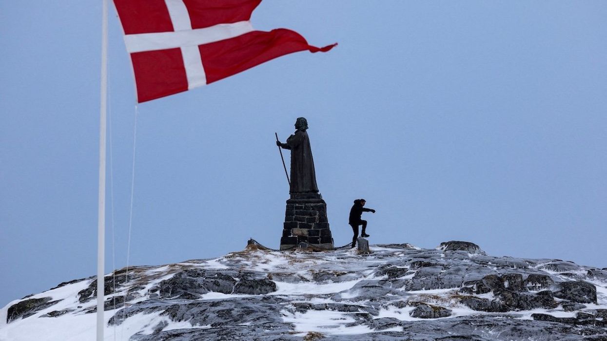 A man walks as a Danish flag flutters next to Hans Egede Statue ahead of a March 11 general election in Nuuk, Greenland, March 9, 2025.