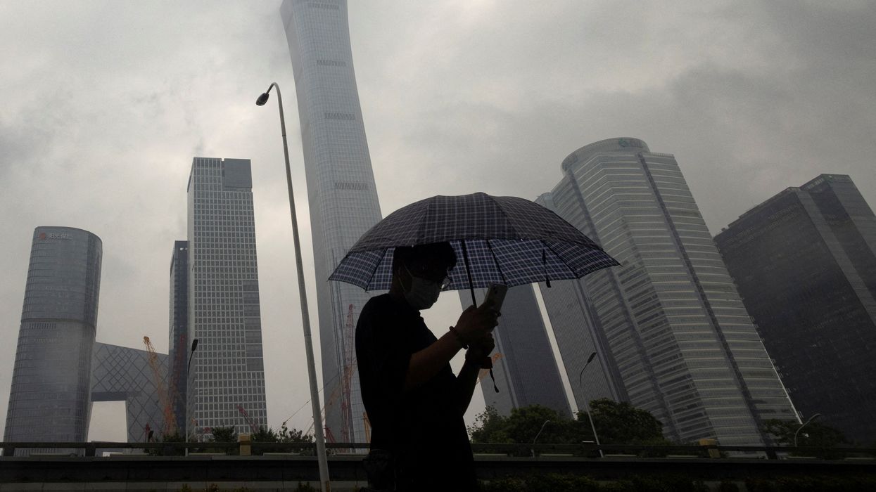 A man walks in the Central Business District on a rainy day, in Beijing, China, July 12, 2023.