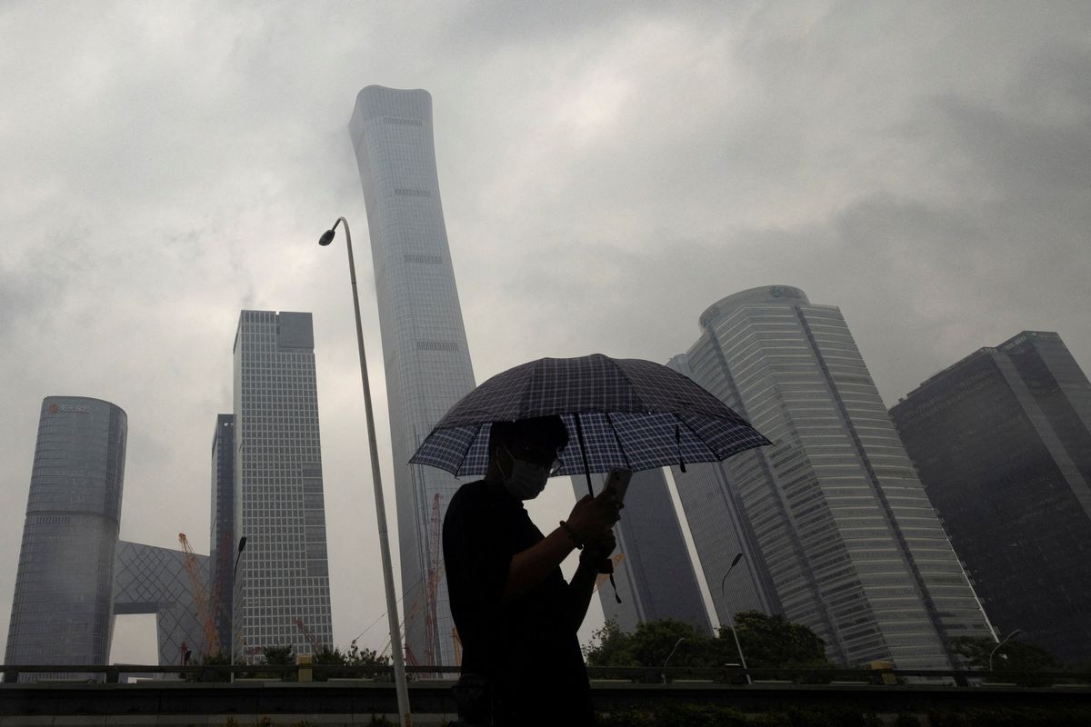 A man walks in the Central Business District on a rainy day in Beijing, China.