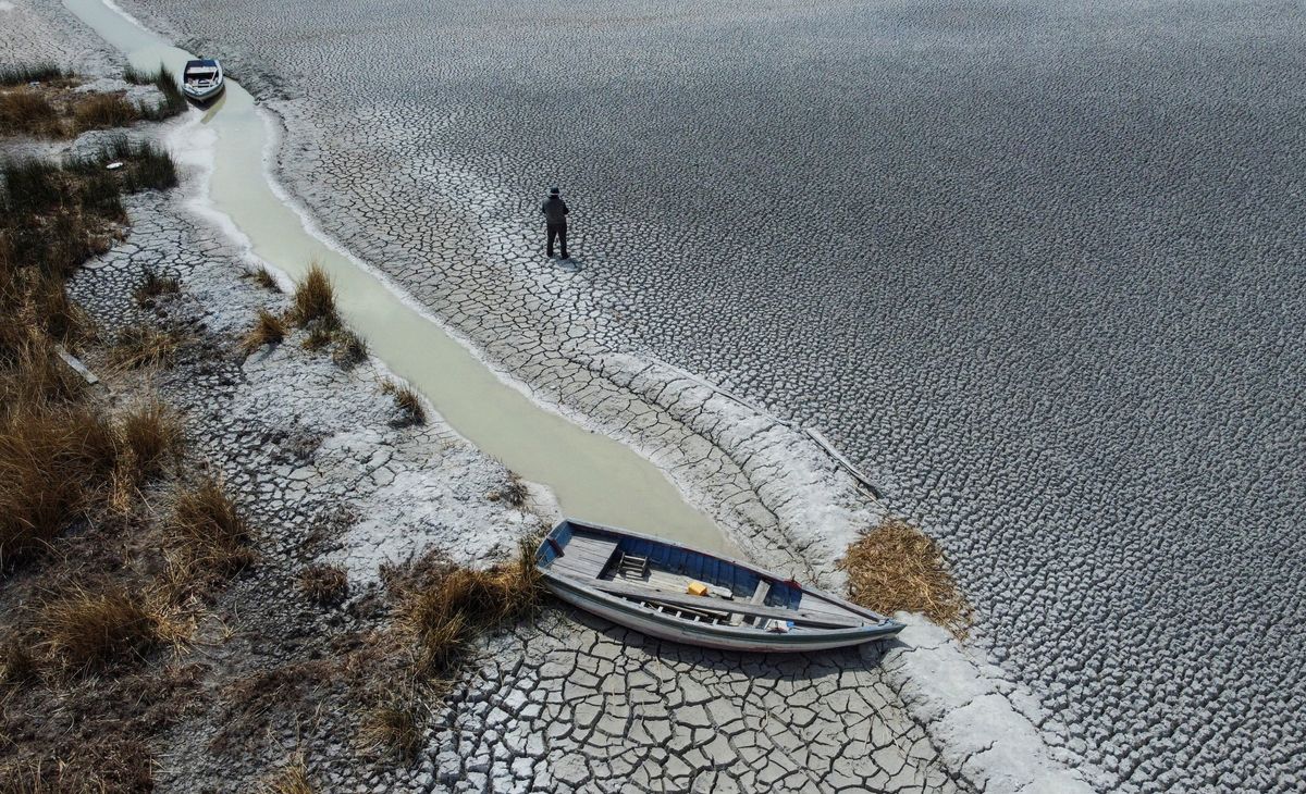 A man walks on a dry area that shows the drop in the level of Lake Titicaca, Latin America's largest freshwater basin, as it is edging towards record low levels, on Cojata Island, Bolivia, in October 2023. 