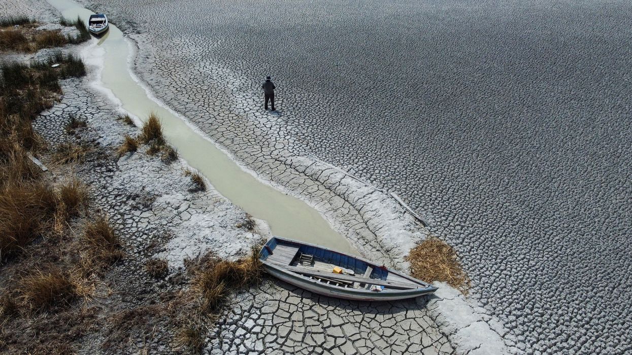 A man walks on a dry area that shows the drop in the level of Lake Titicaca, Latin America's largest freshwater basin, as it is edging towards record low levels, on Cojata Island, Bolivia, in October 2023.