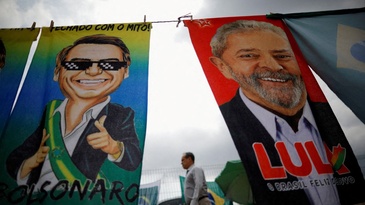 A man walks past Brazilian presidential campaign materials showing candidates Lula and Bolsonaro in Brasilia.
