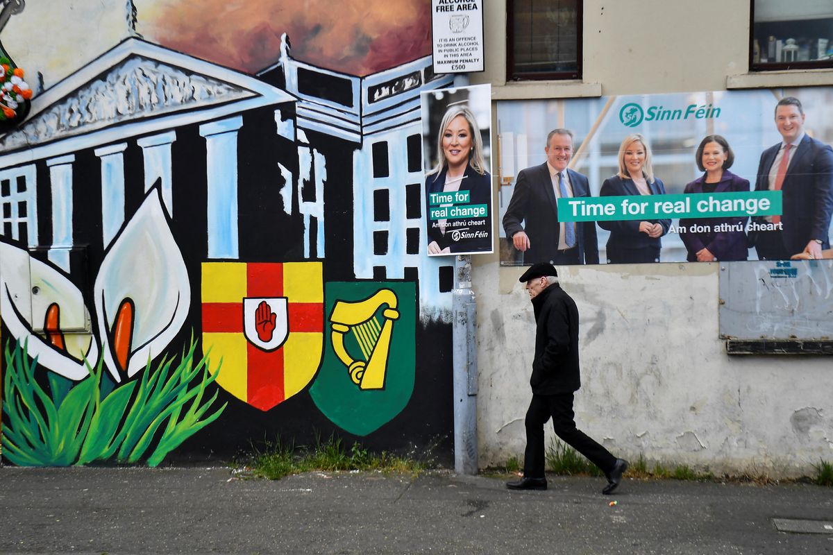 A man walks past Sinn Fein election posters along the nationalist Falls Road in Belfast.