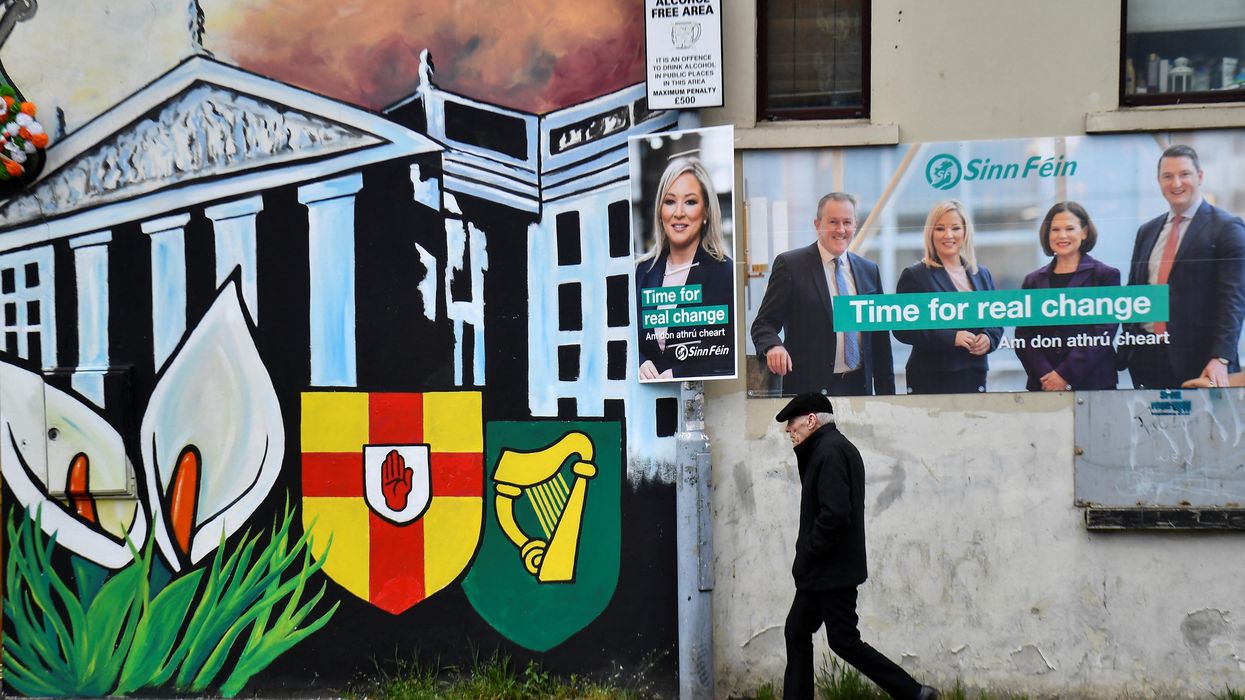 A man walks past Sinn Fein election posters along the nationalist Falls Road in Belfast.