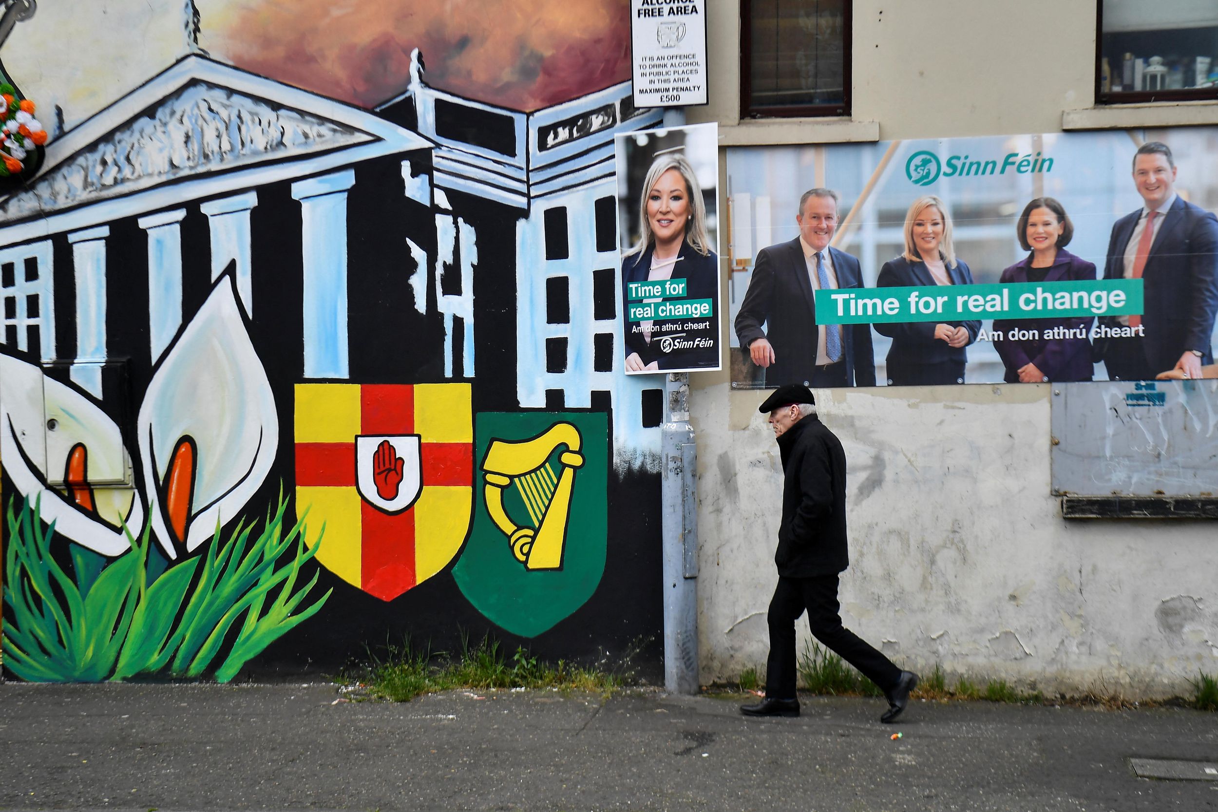 A man walks past Sinn Fein election posters along the nationalist Falls Road in Belfast.