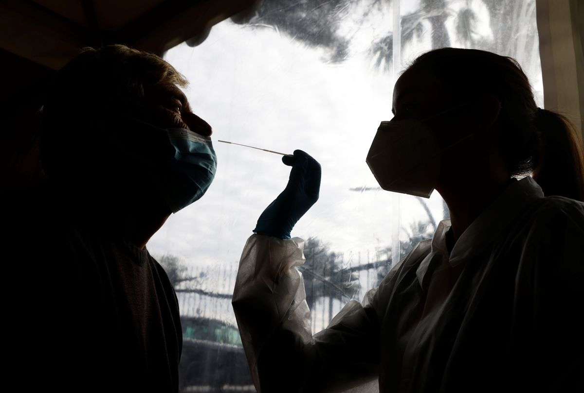 A medical worker administers a nasal swab to a patient at a coronavirus disease (COVID-19) testing center 