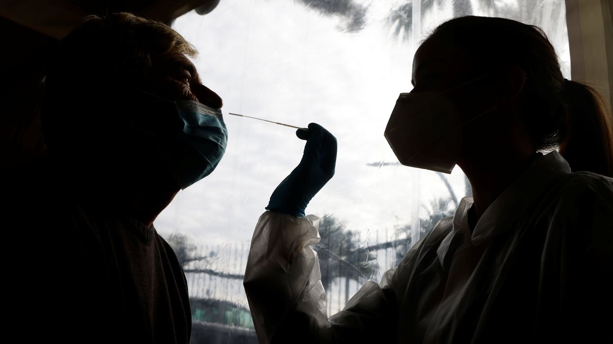 A medical worker administers a nasal swab to a patient at a coronavirus disease (COVID-19) testing center