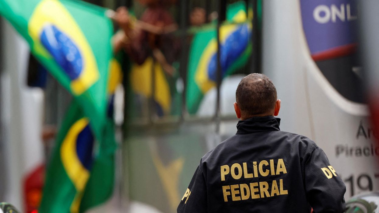 A member of the Federal Police looks on as supporters of Brazil's former President Jair Bolsonaro arrive on a bus after their camp was dismantled in Brasilia.