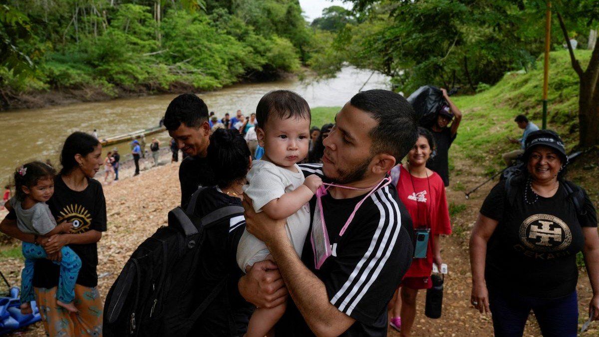 ​A migrant carries his child after crossing the Darien Gap in Lajas Blancas, Darien Province, Panama, on September 26, 2024.