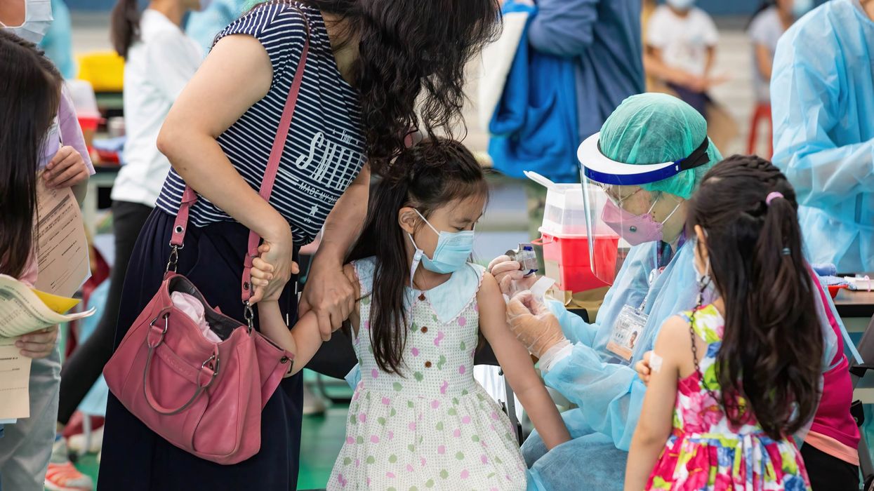 A mother holds her daughter's arm as a healthcare worker administers the child with Pfizer-BNT covid-19 vaccine in Taiwan.