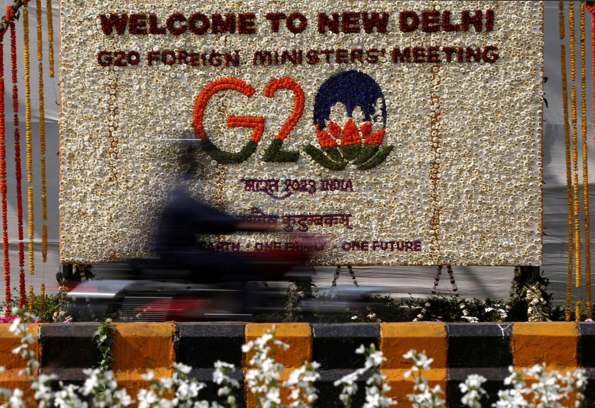 A motorist rides past a hoarding decorated with flowers to welcome G20 foreign ministers in New Delhi, India, March 1, 2023.