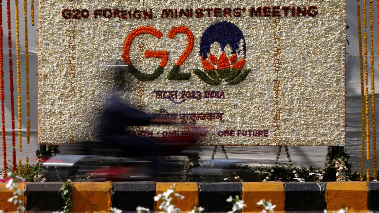 A motorist rides past a hoarding decorated with flowers to welcome G20 foreign ministers in New Delhi, India, March 1, 2023.