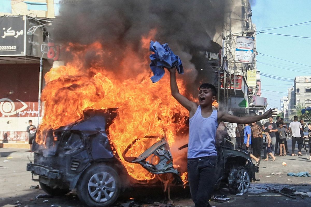 ​A Palestinian boy reacts next to a burning Israeli vehicle that Palestinian gunmen brought to Gaza after they infiltrated areas of southern Israel on Saturday. 