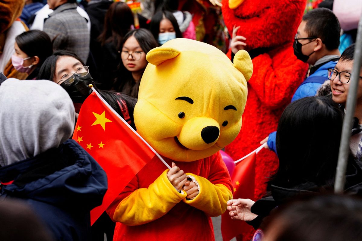 A parade participant in a Winnie the Pooh costume waves a Chinese flag before the Lunar New Year parade in the Chinatown neighborhood of New York, U.S., February 12, 2023.