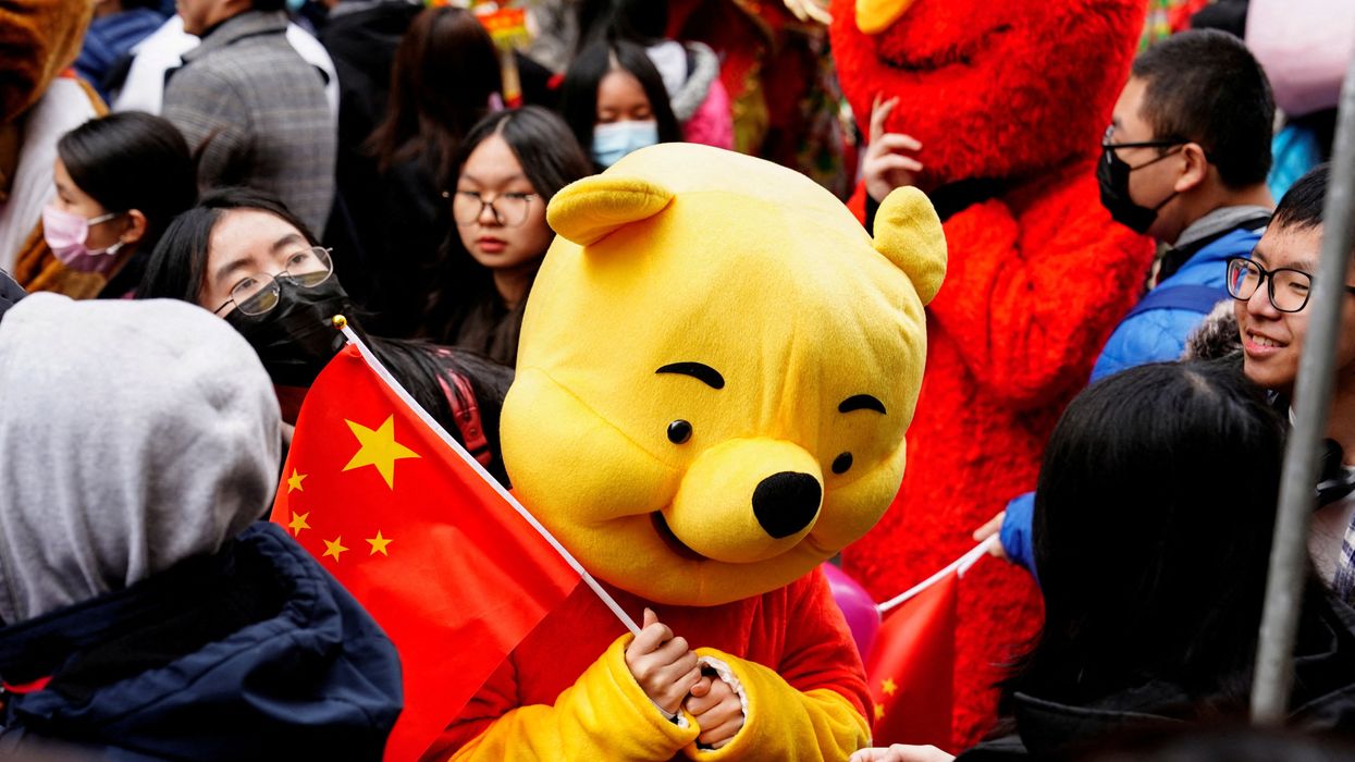 A parade participant in a Winnie the Pooh costume waves a Chinese flag before the Lunar New Year parade in the Chinatown neighborhood of New York, U.S., February 12, 2023.