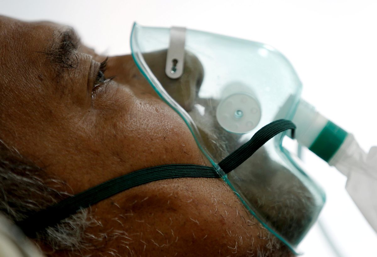A patient suffering from the coronavirus disease (COVID-19) breathes with a non-rebreather mask in an isolation room at a hospital in Bogor, Indonesia January 26, 2021.