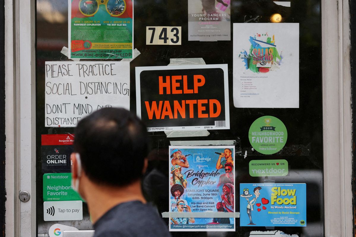 A pedestrian passes a "Help Wanted" sign in the door of a hardware store in Cambridge, Massachusetts.
