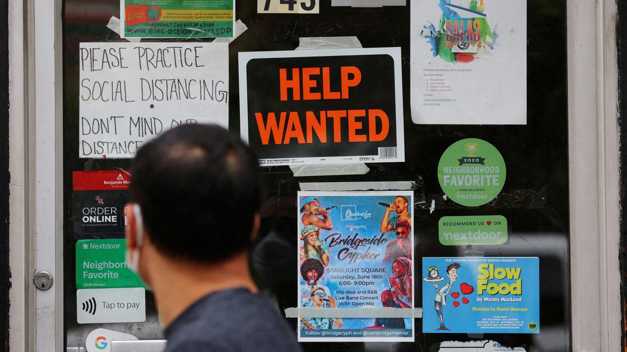 A pedestrian passes a "Help Wanted" sign in the door of a hardware store in Cambridge, Massachusetts.