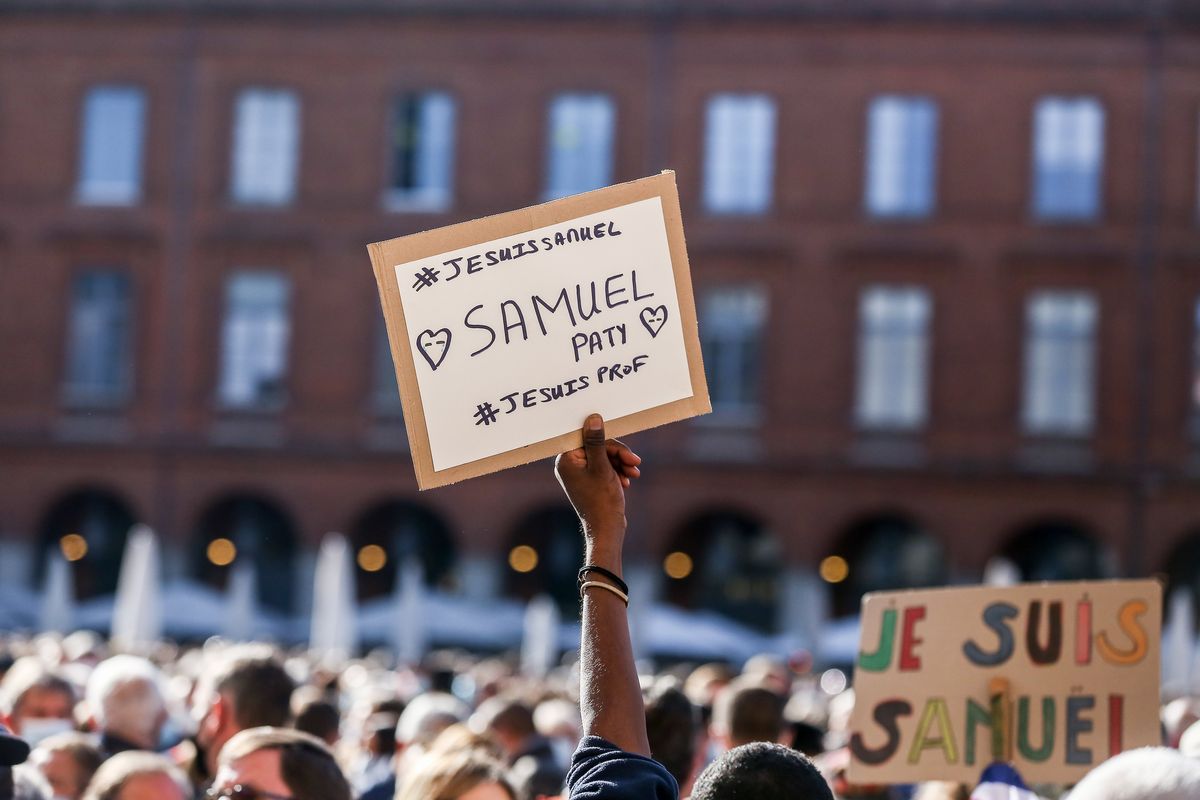 A person carries a sign during a  rally in Paris for Samuel Paty, beheaded for showing caricatures from the satirical newspaper Charlie Hebdo to his students. Reuters