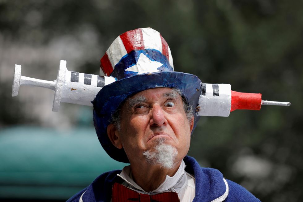 A person dressed as Uncle Sam with a large medical syringe  going through his hat, attends an anti-mandatory COVID-19 vaccine protest held outside New York City Hall in Manhattan, New York