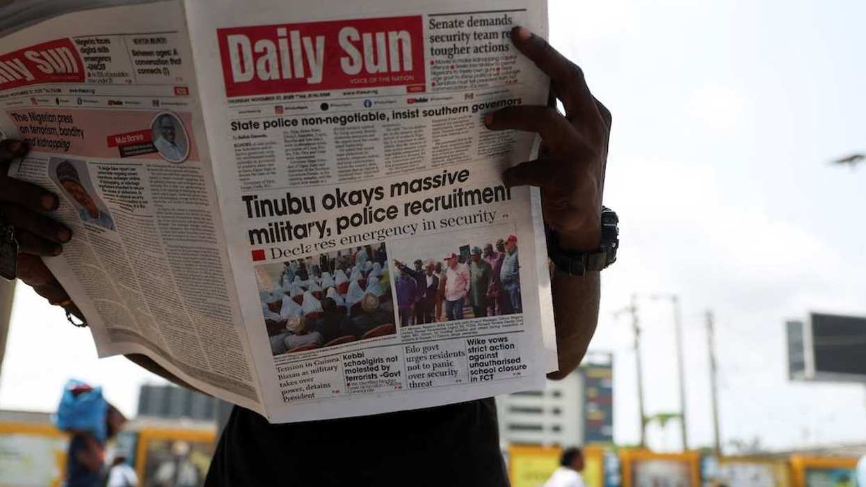 A person reads a newspaper at a roadside newspaper stand in Ikoyi Lagos, Nigeria, November 27, 2025.