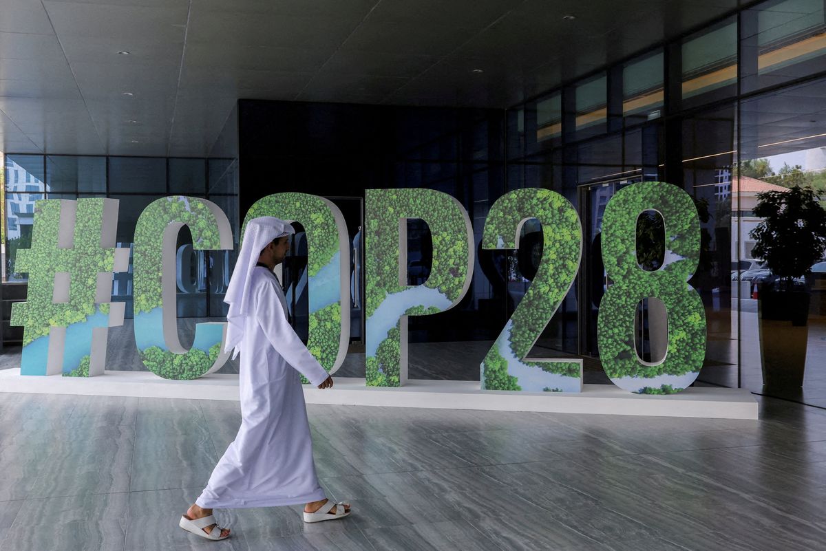 A person walks past a "#COP28" sign in Abu Dhabi, United Arab Emirates.