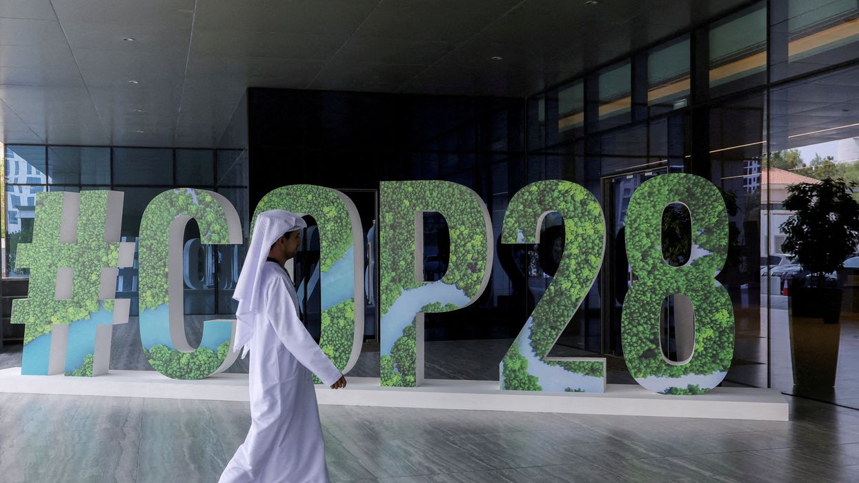 A person walks past a "#COP28" sign in Abu Dhabi, United Arab Emirates.