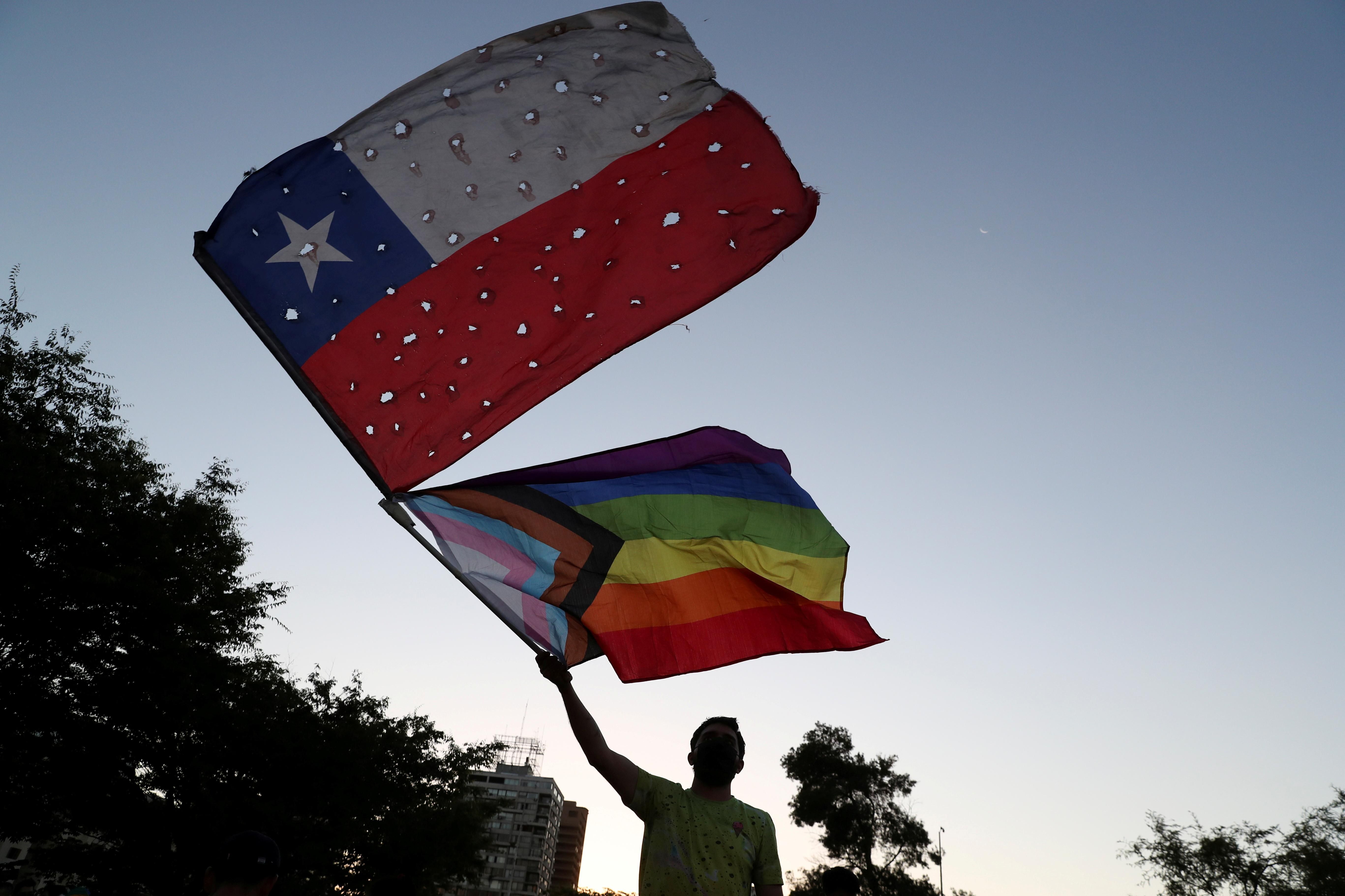 A person waves flags as people gather after the Senate approved a same-sex marriage bill, in Santiago, Chile December 7, 2021