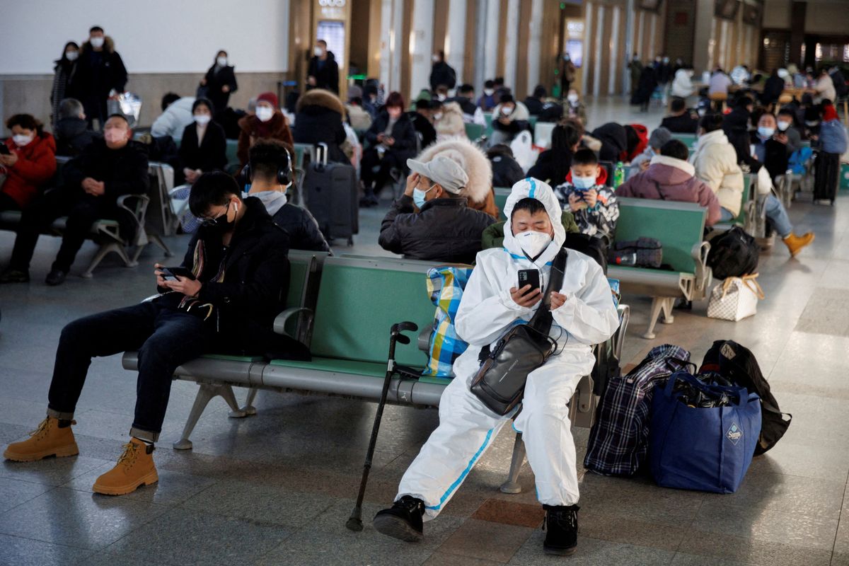 A person wearing a protective suit sits in the Beijing Railway Station after China lifted its COVID-19 restrictions in Beijing, January 20, 2023.