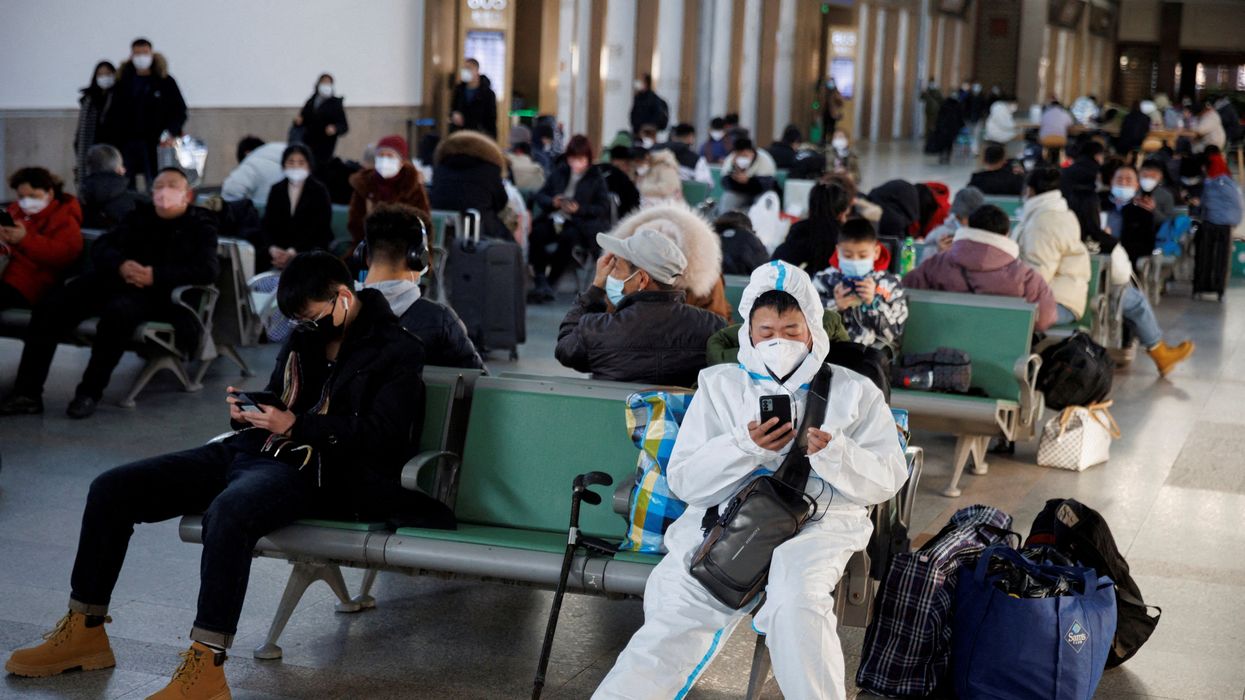 A person wearing a protective suit sits in the Beijing Railway Station after China lifted its COVID-19 restrictions in Beijing, January 20, 2023.