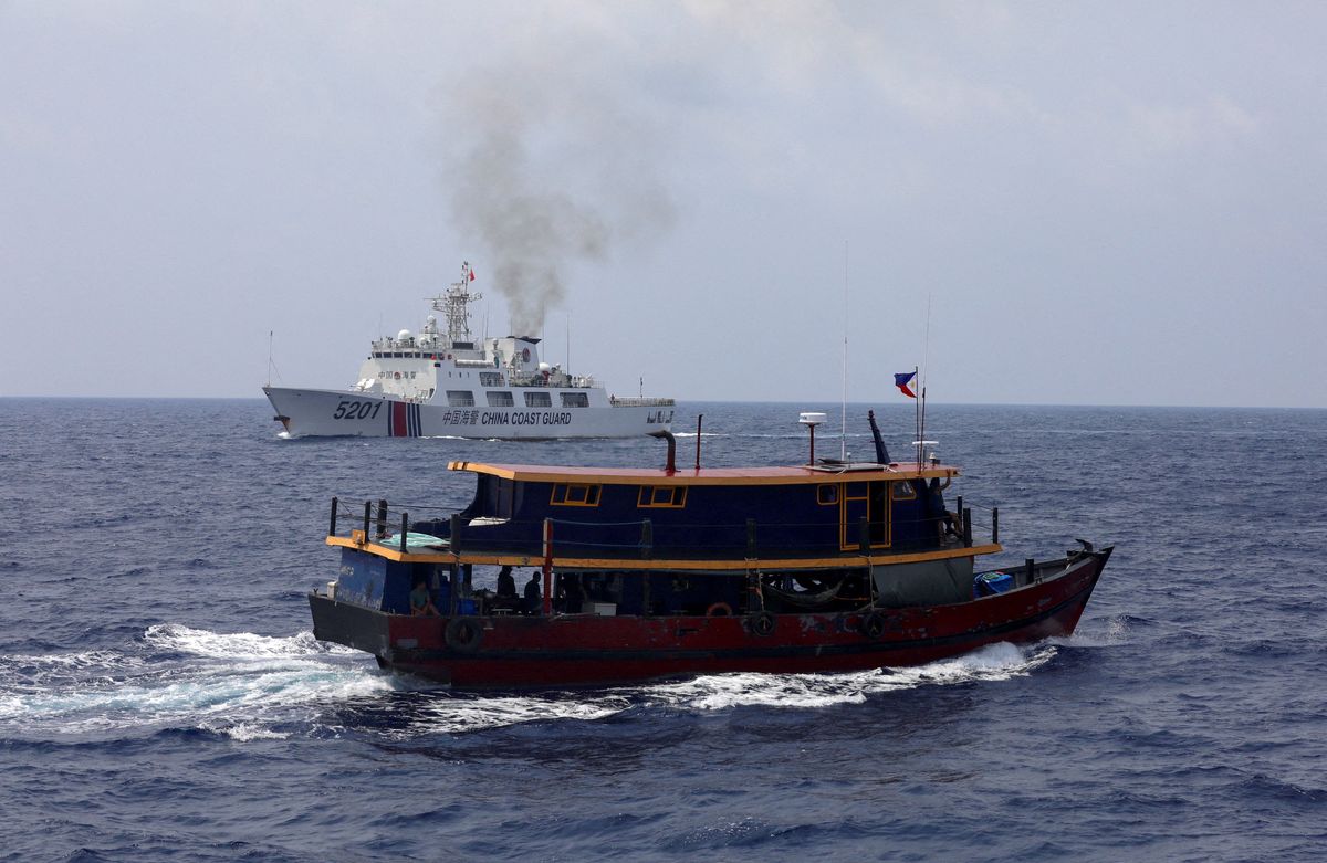 A Philippine supply boat sails near a Chinese Coast Guard ship during a resupply mission for Filipino troops stationed at a grounded warship in the South China Sea, on Oct. 4, 2023. 