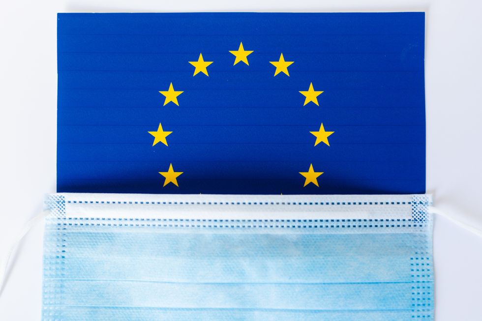 a photo of a European Union flag on top with bottom covered with a medical mask
