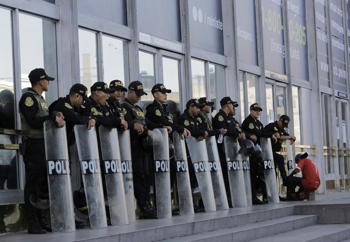 A police officer gets his shoes shined as he and fellow officers stand outside the prosecutor's office before the arrival of Peru's President Dina Boluarte, in Lima, Peru March 7, 2023. 