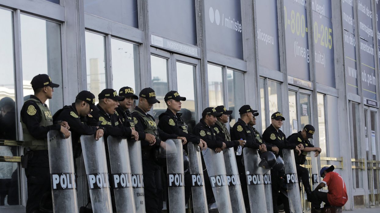 A police officer gets his shoes shined as he and fellow officers stand outside the prosecutor's office before the arrival of Peru's President Dina Boluarte, in Lima, Peru March 7, 2023.