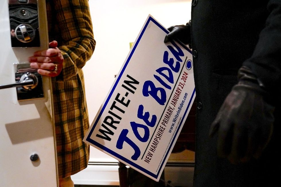 ​A potential voter takes home a sign after attending a house party supporting the write-in campaign to put US President Joe Biden's name on the New Hampshire Democratic primary ballot. 
