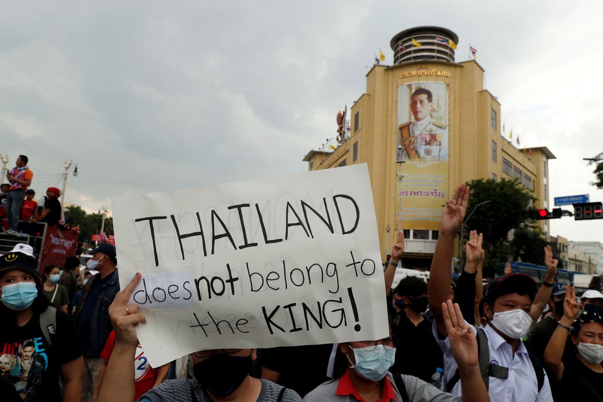 A pro-democracy demonstrator holds a placard past a portrait of Thai King Vajiralongkorn in Bangkok. Reuters