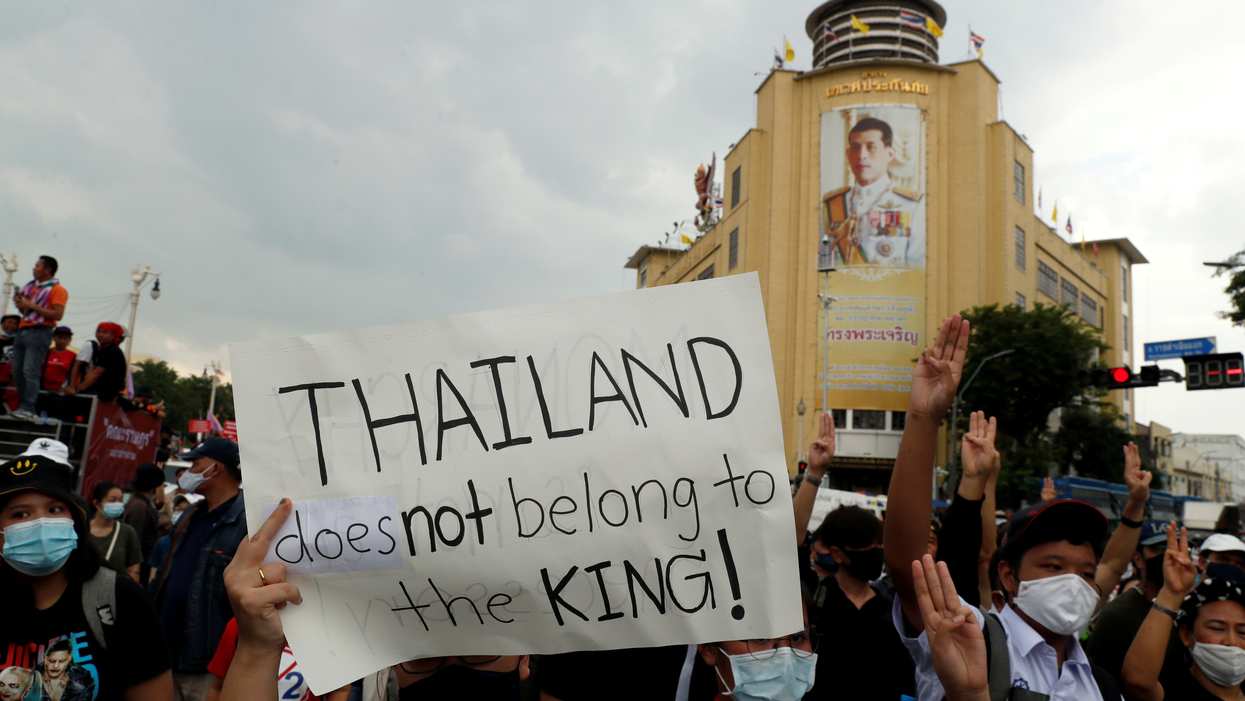 A pro-democracy demonstrator holds a placard past a portrait of Thai King Vajiralongkorn in Bangkok. Reuters