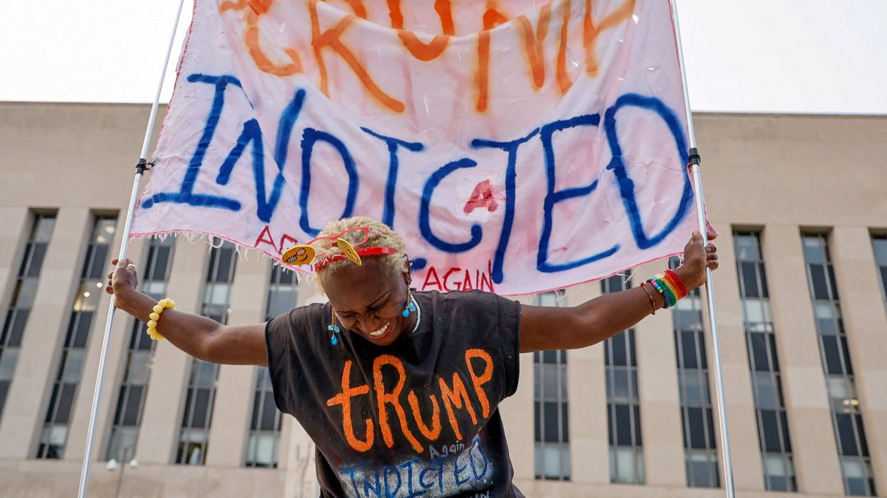 A protester holds a banner that says "Trump indicted."