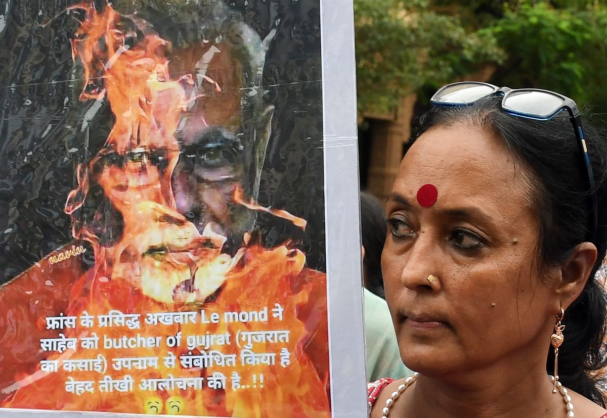 A protester holds a placard showing an image of burning PM Narendra Modi during a demonstration against the Manipur violence in Mumbai, India.