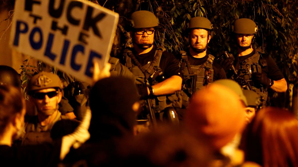 A protester holds up a sign as law enforcement personnel look on during a rally against the death in Minneapolis police custody of George Floyd, in Washington, DC.