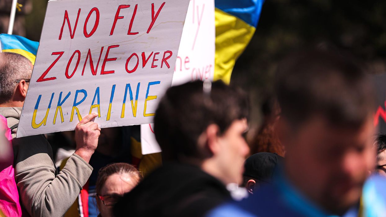 A protester holds up a sign calling for NATO to create a no-fly zone over Ukraine.
