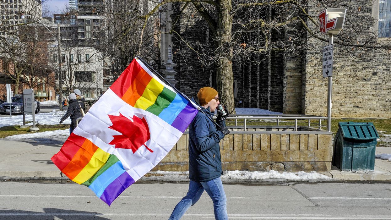 A protester is seen carrying a Canadian rainbow flag.