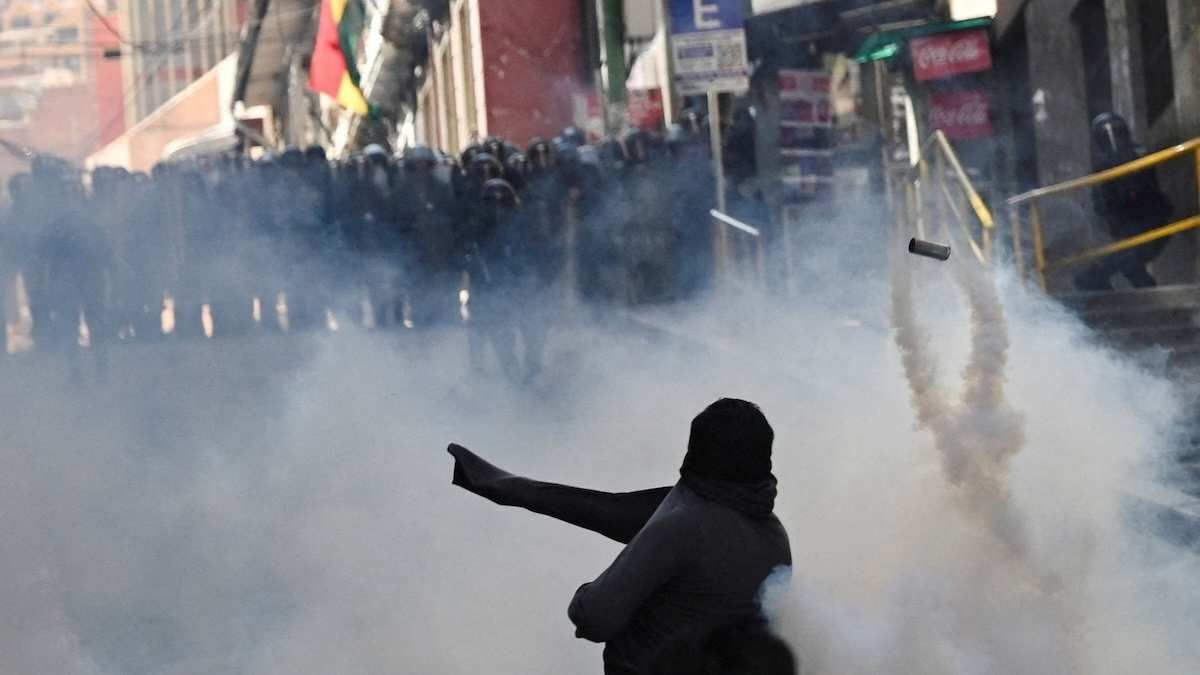 A protestor throws a tear gas canister back towards the police