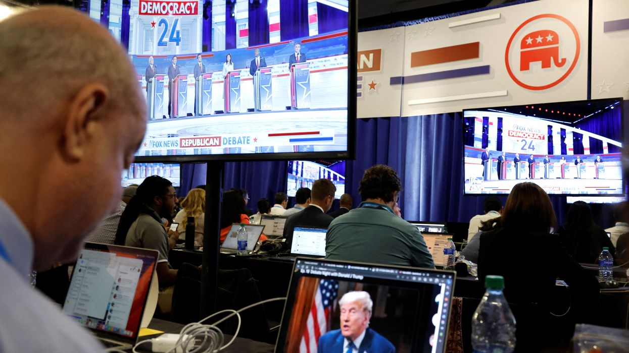 A reporter watches former President Donald Trump's online interview during the first Republican candidates' debate of the 2024 U.S. presidential campaign.