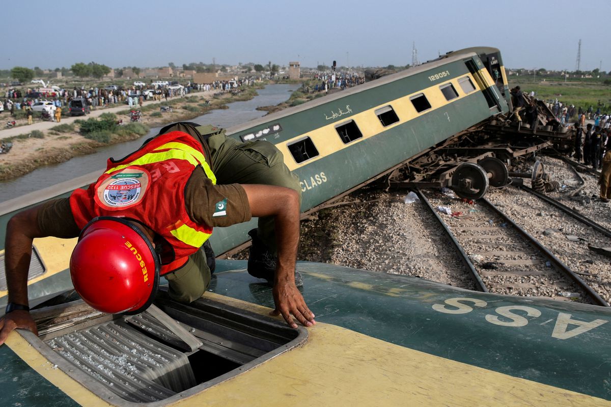 ​A rescue worker searches for victims after a train derailed in District Sanghar in the Sindh province of Pakistan.