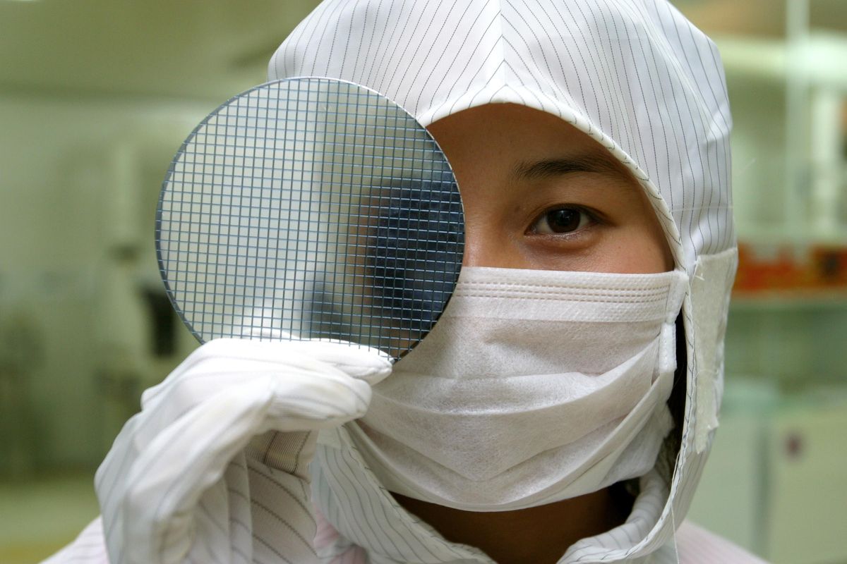 a researcher wearing cleanroom suit displaying a wafer in the lab of Shanghai Microsemi Semiconductor Co., Ltd. in Shanghai, China.