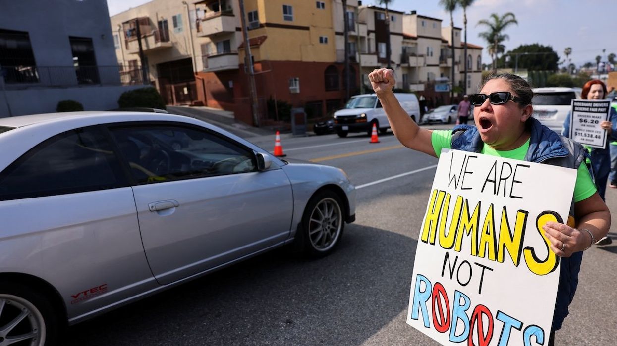 A rideshare driver in Los Angeles holds a placard, as Uber, Lyft, and DoorDash drivers strike in multiple US cities on Valentine's Day.